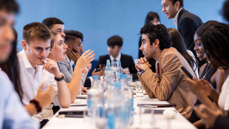 Group of Lazard Interns Talking at Long Table