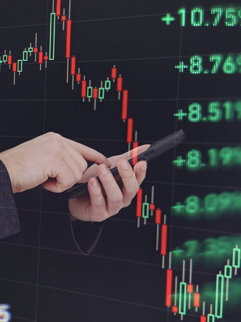 Person holding the phone with the market screens around and behind them